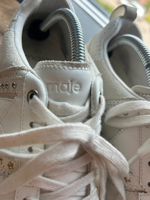 Białe skórzane sneakersy damskie Maje ze srebrnymi nitami i tłoczonym logo na języku, dostępne w sklepie AVEXI.