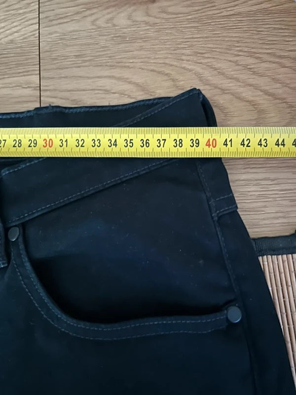 Czarne jeansy męskie Wrangler Arizona z oferty AVEXI, widoczny pomiar szerokości w pasie miarką krawiecką.